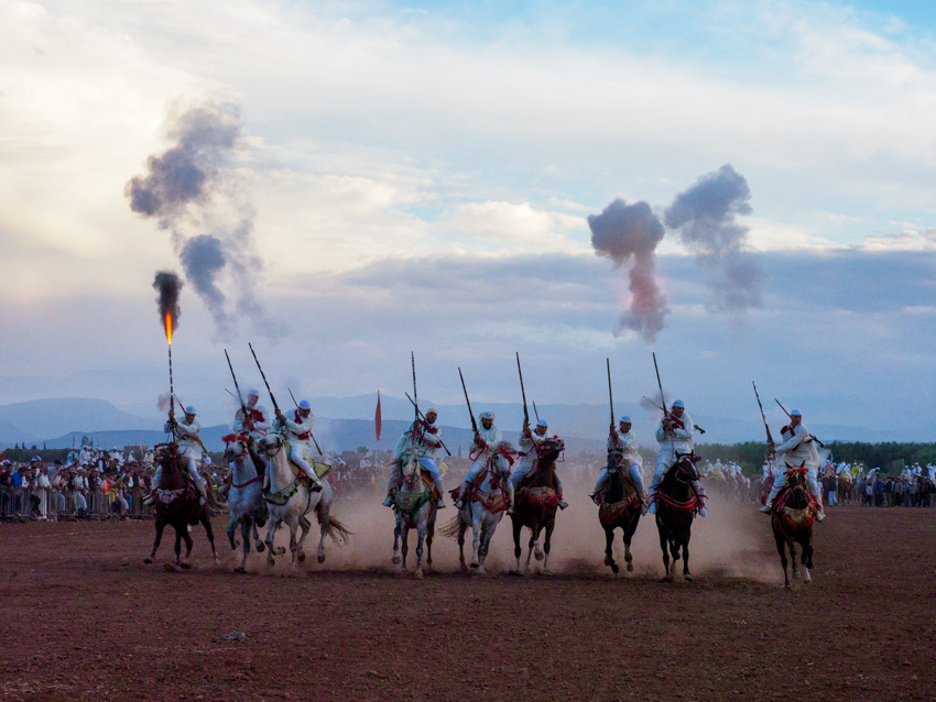 Jinetes marroquíes durante una exhibición de Tbourida con caballos al galope y descarga de pólvora.