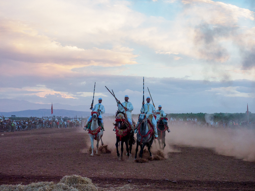 Jinetes marroquíes durante una exhibición de Tbourida con caballos al galope y descarga de pólvora.