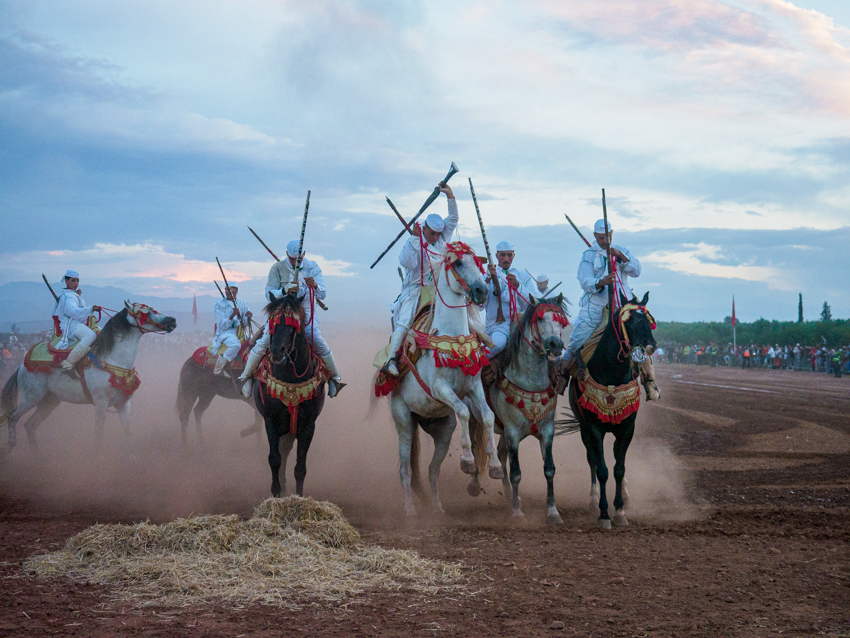 Jinetes marroquíes durante una exhibición de Tbourida con caballos al galope y descarga de pólvora.