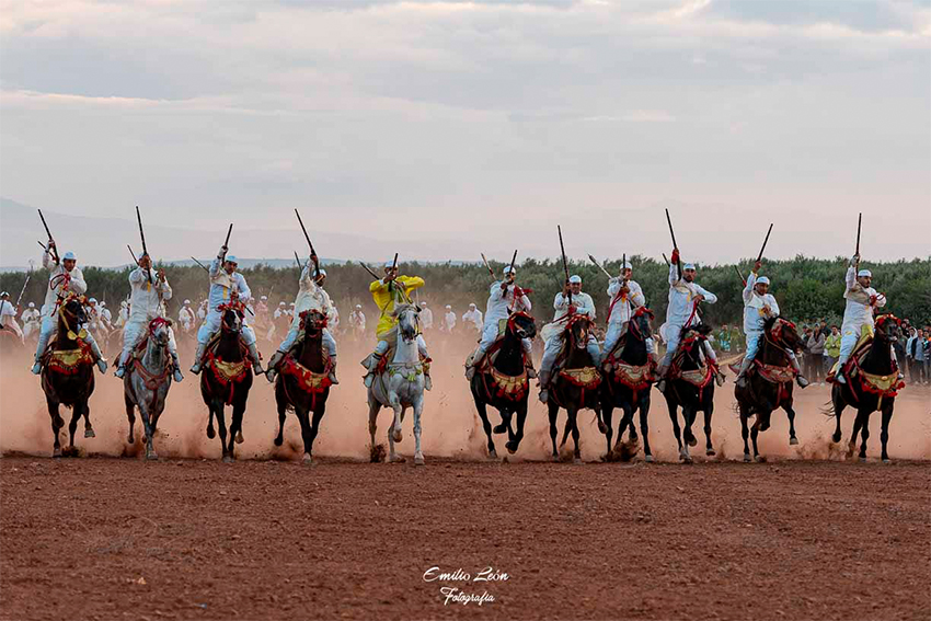 Jinetes marroquíes durante una exhibición de Tbourida con caballos al galope y descarga de pólvora.